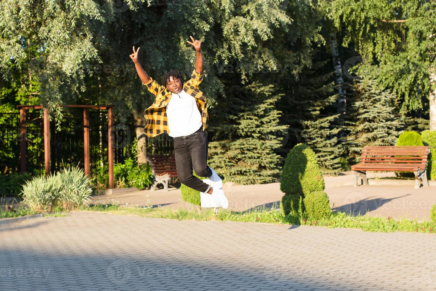 una mujer afroamericana feliz en el parque da un salto en el verano foto