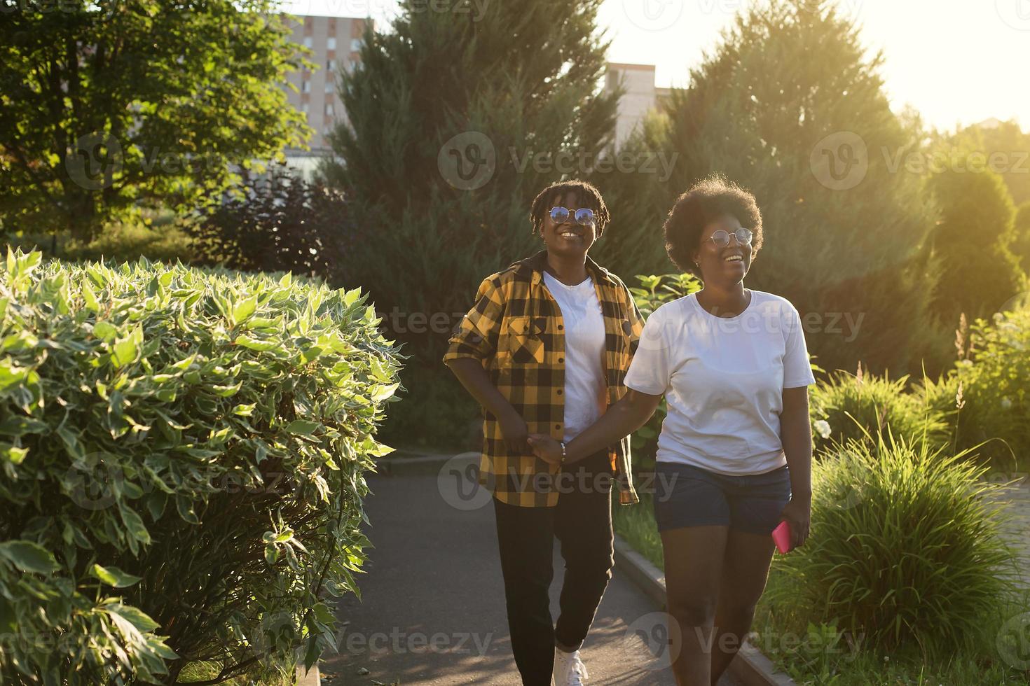 two happy African-American women are walking down the street photo