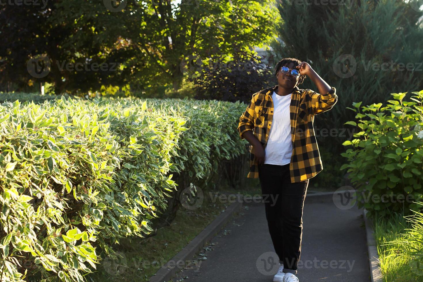 Feliz mujer afroamericana camina por la calle en el verano foto