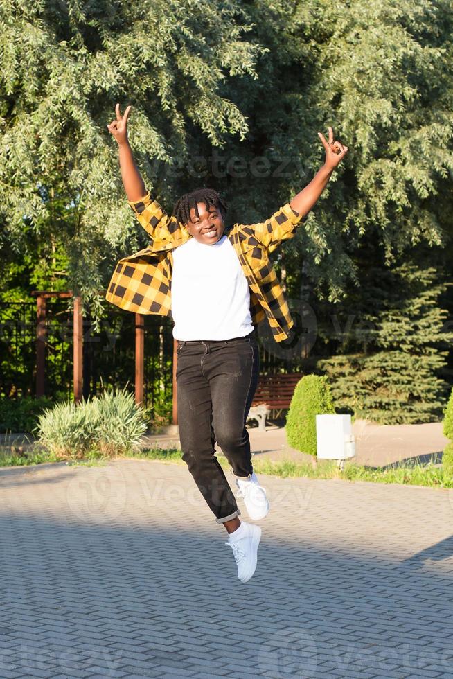 a happy African American woman in the park makes a jump in the summer photo