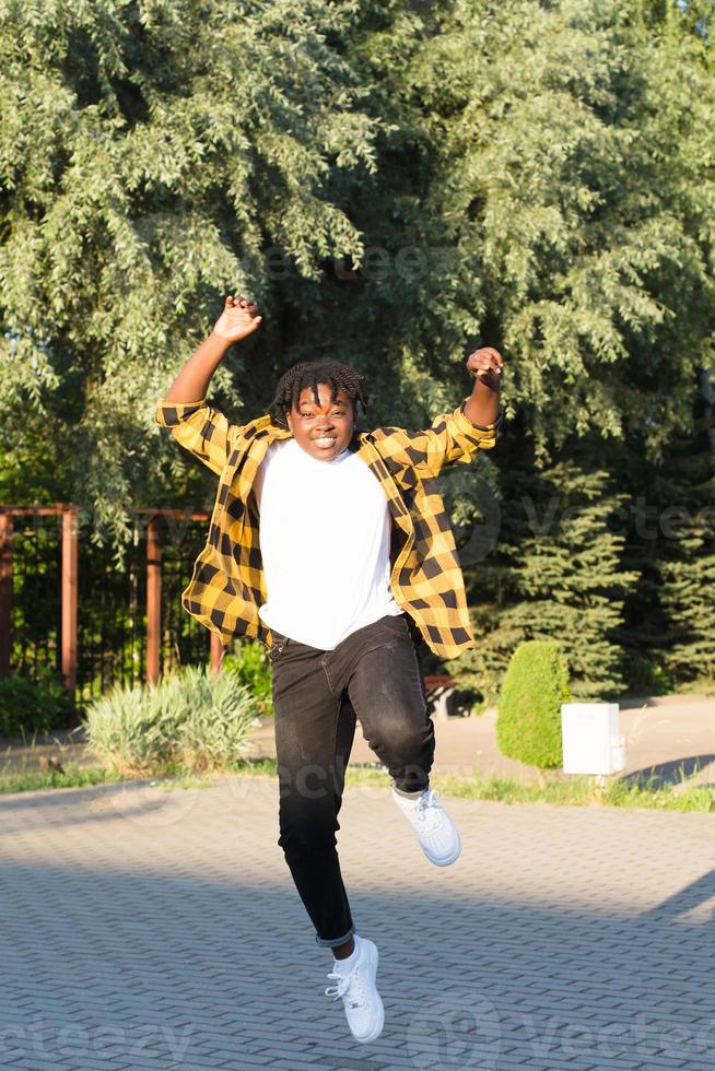 a happy African American woman in the park makes a jump in the summer photo