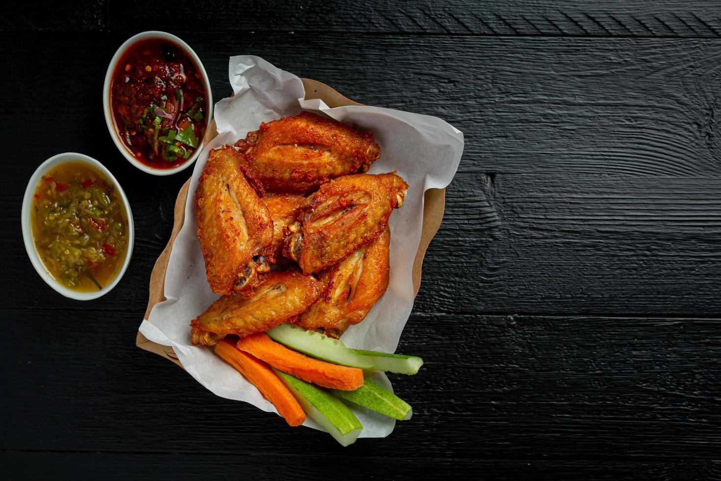 Chicken wings in paper box on a black photo