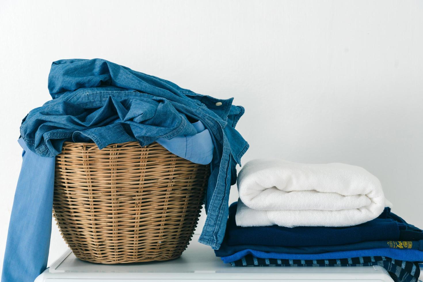 Close up clothes in basket and pile fabric on washing machine photo