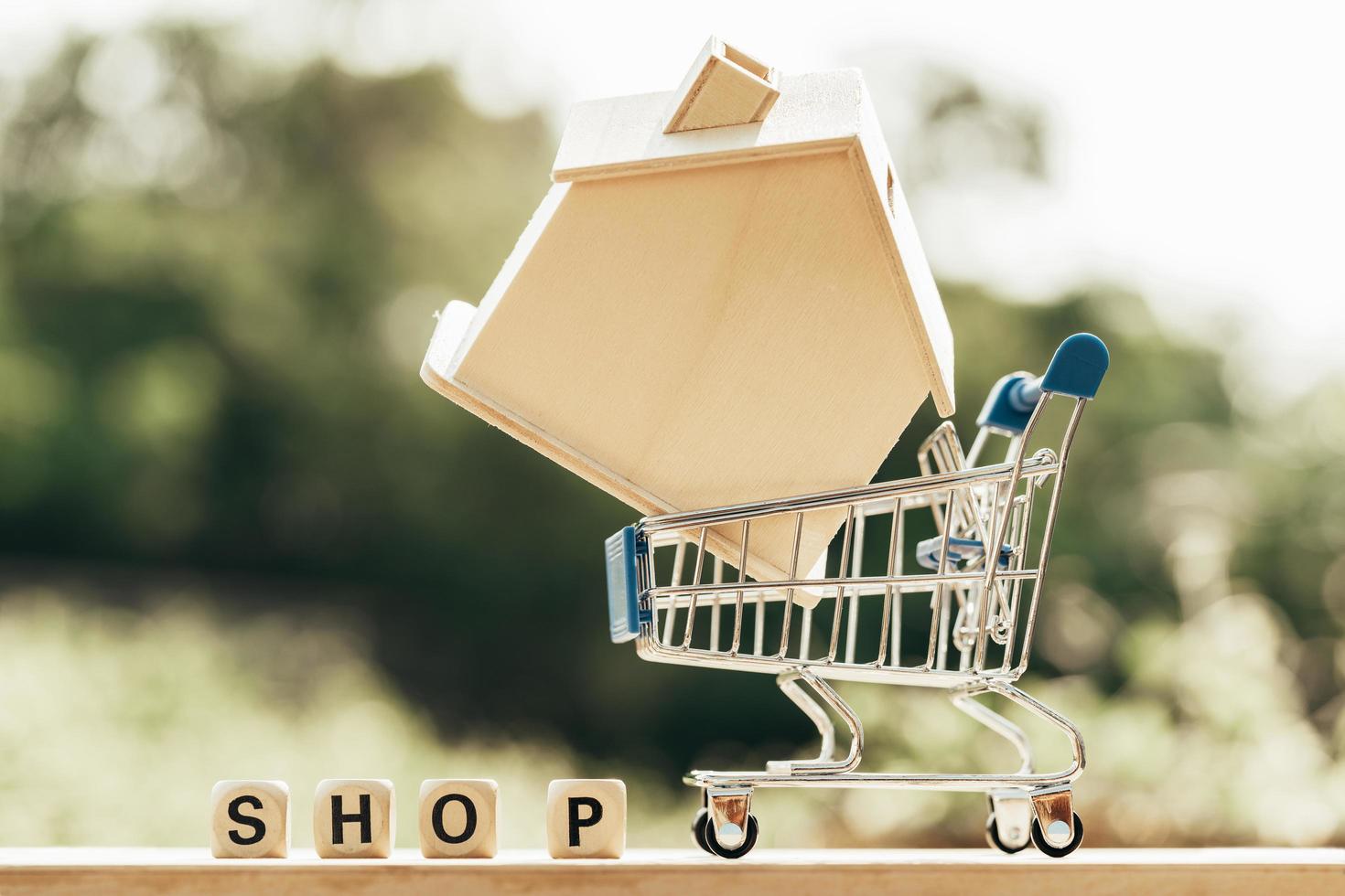 Miniatura con simulacro de casa de madera en carrito de compras y block word shop foto