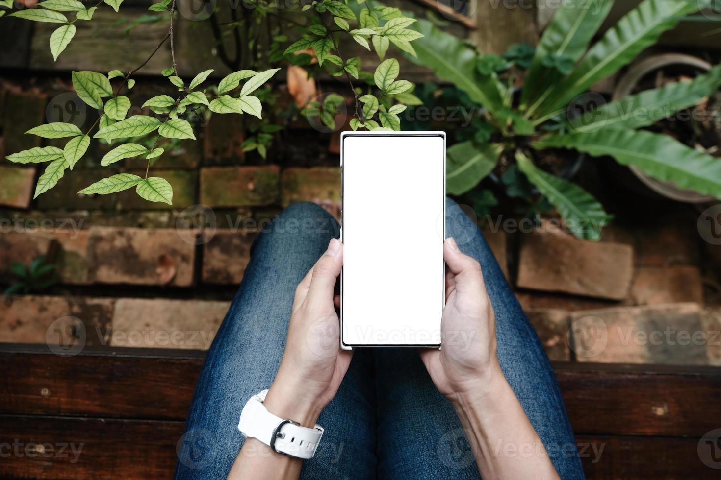 mano de mujer sosteniendo teléfono inteligente con pantalla en blanco foto