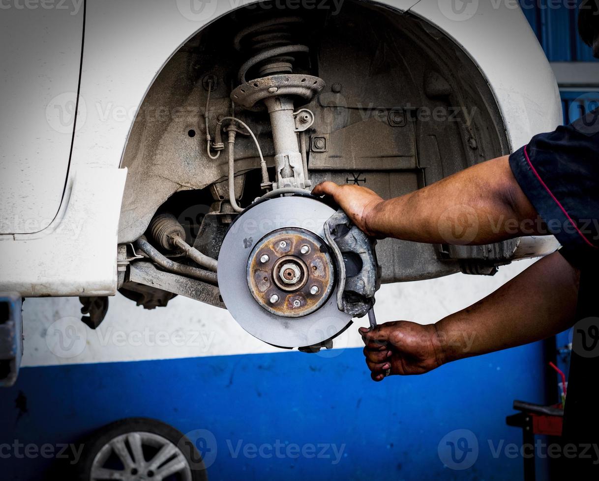 Mechanic man repairing brake disc brakes wheel of cars photo