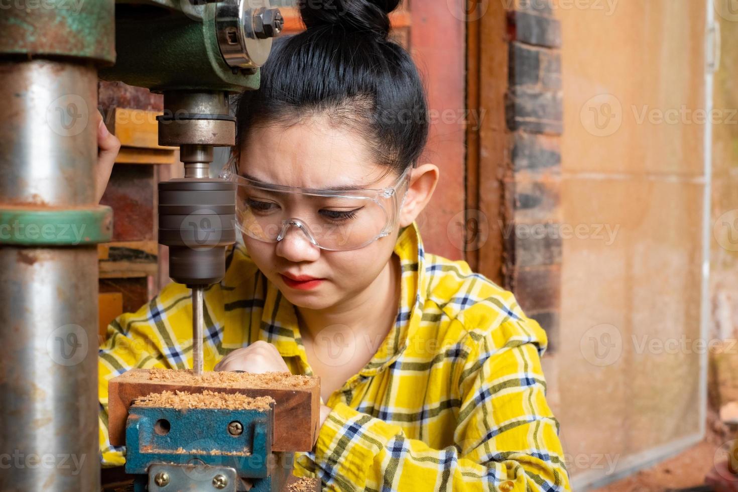 las mujeres de pie es artesanía trabajando madera de taladro foto