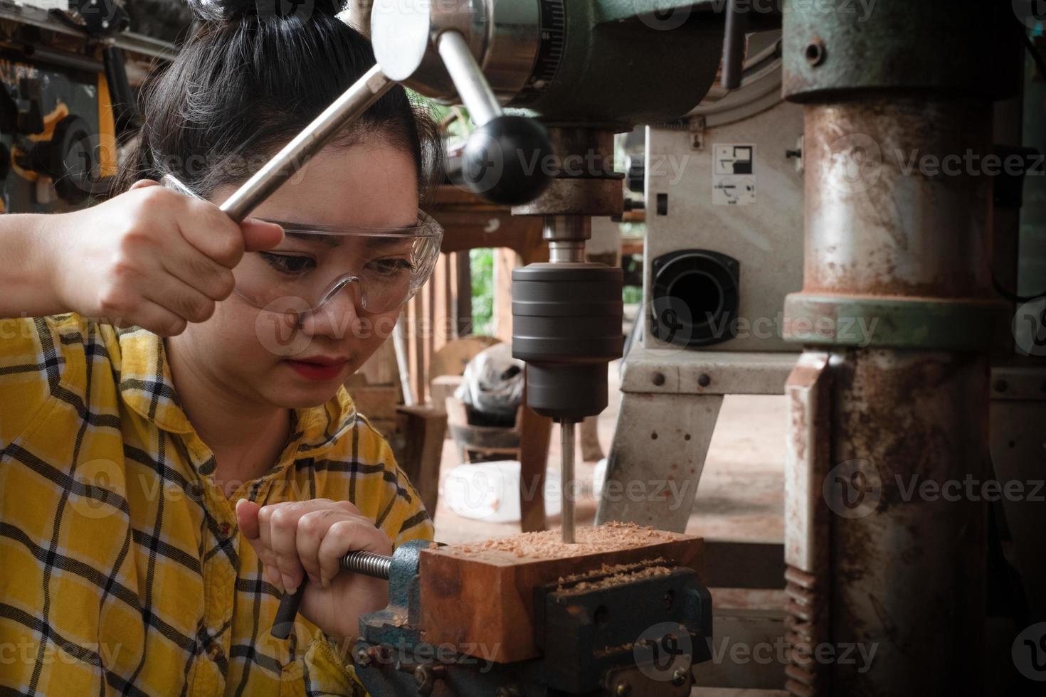 las mujeres de pie es artesanía trabajando madera de taladro foto