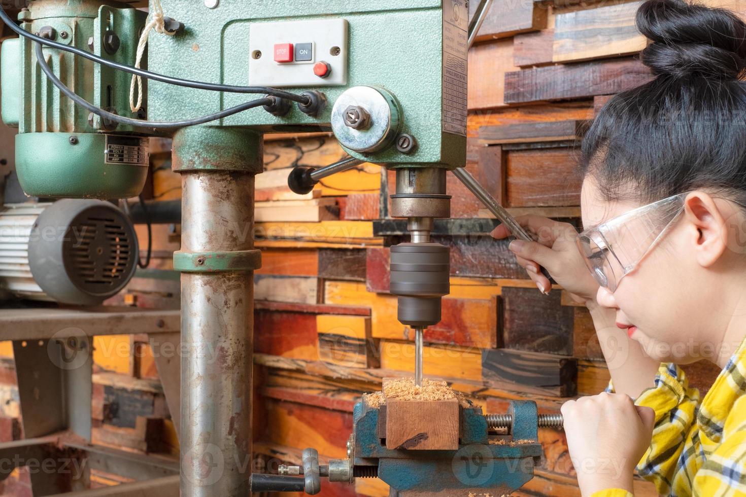 las mujeres de pie es artesanía trabajando madera de taladro foto