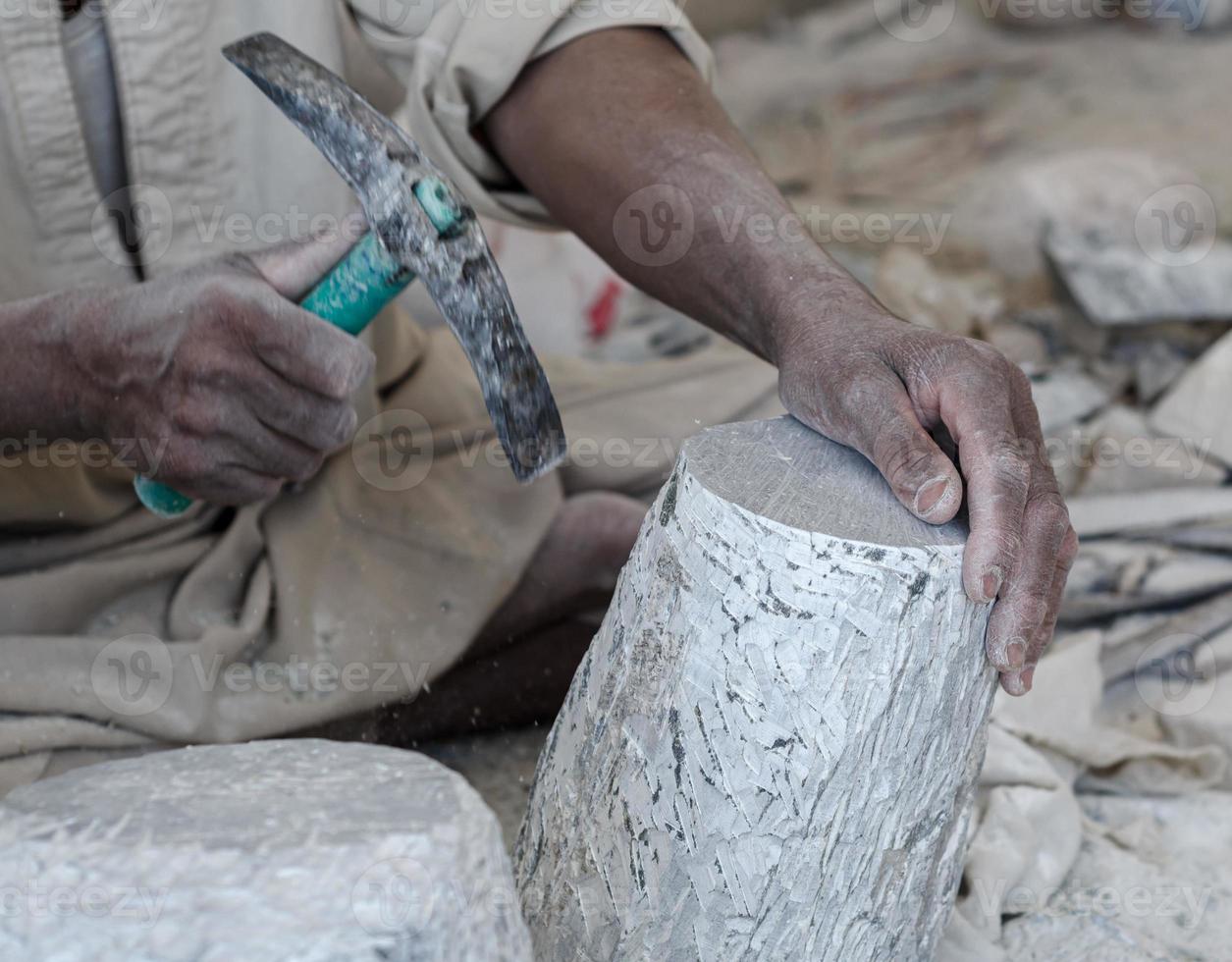 hands of a male Egyptian sculptor while working with a stone alabaster photo