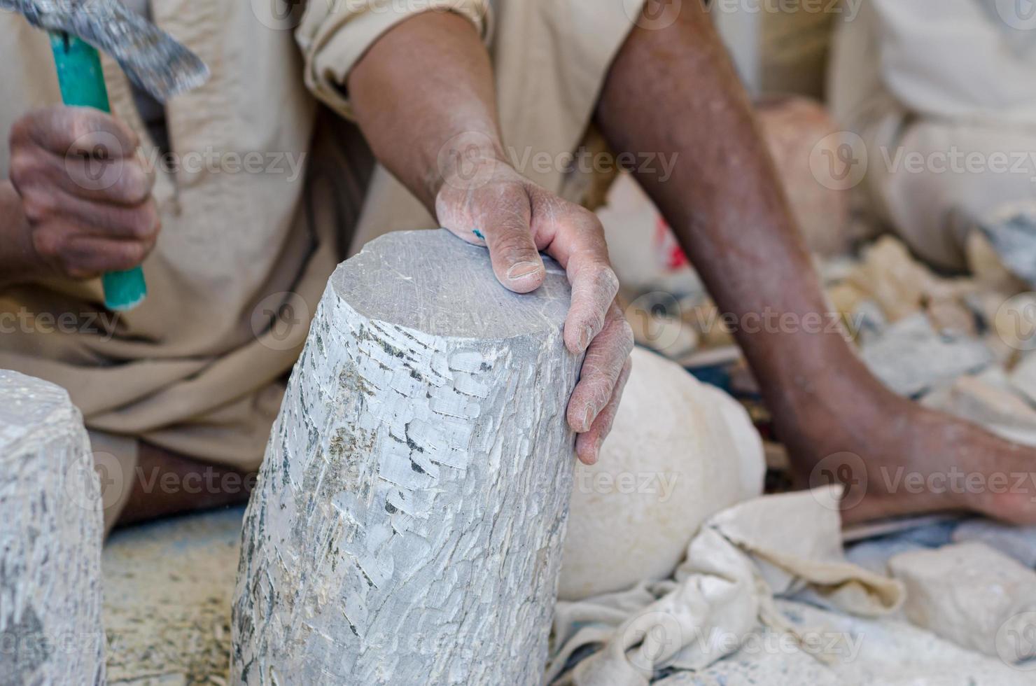 hands of a male Egyptian sculptor while working with a stone alabaster photo