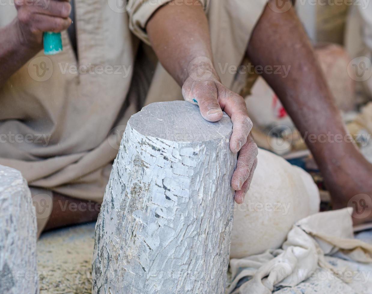 hands of a male Egyptian sculptor while working with a stone alabaster photo