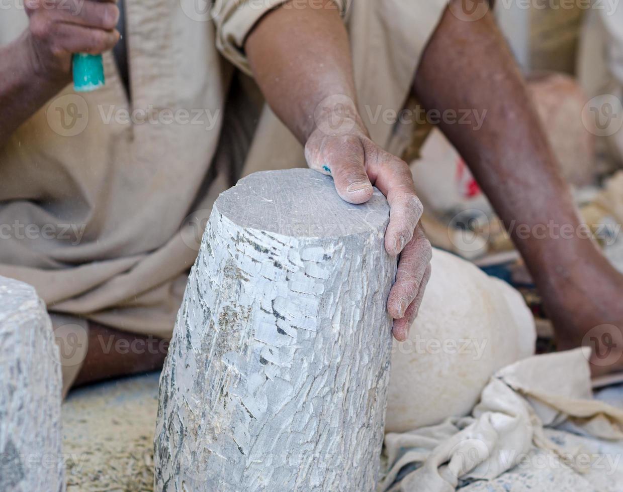 Manos de un escultor egipcio mientras trabajaba con un alabastro de piedra foto