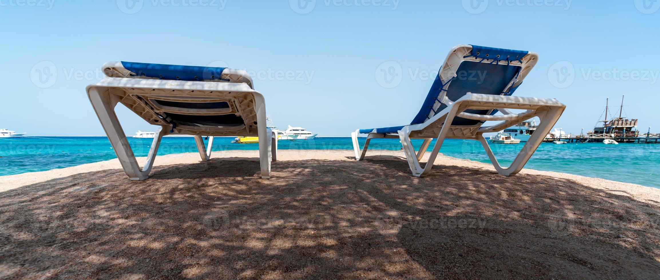 dos tumbonas de playa a la sombra a orillas del mar rojo foto