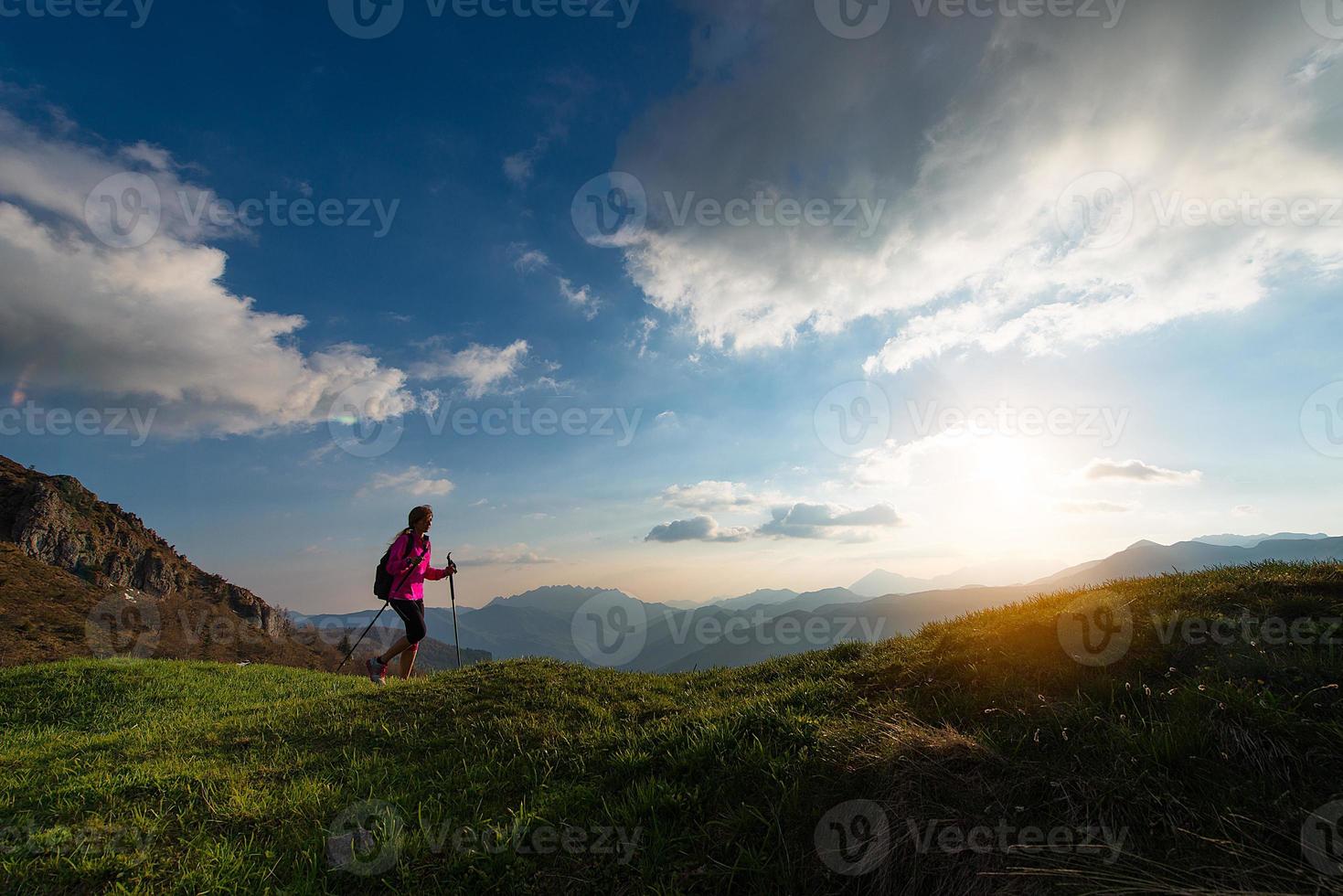 Slender woman practicing nordic walking in the mountains photo