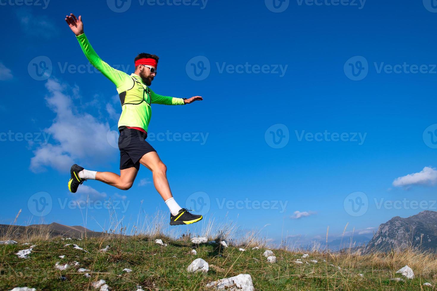 Skyrunner durante un salto cuesta abajo en prados de montaña foto