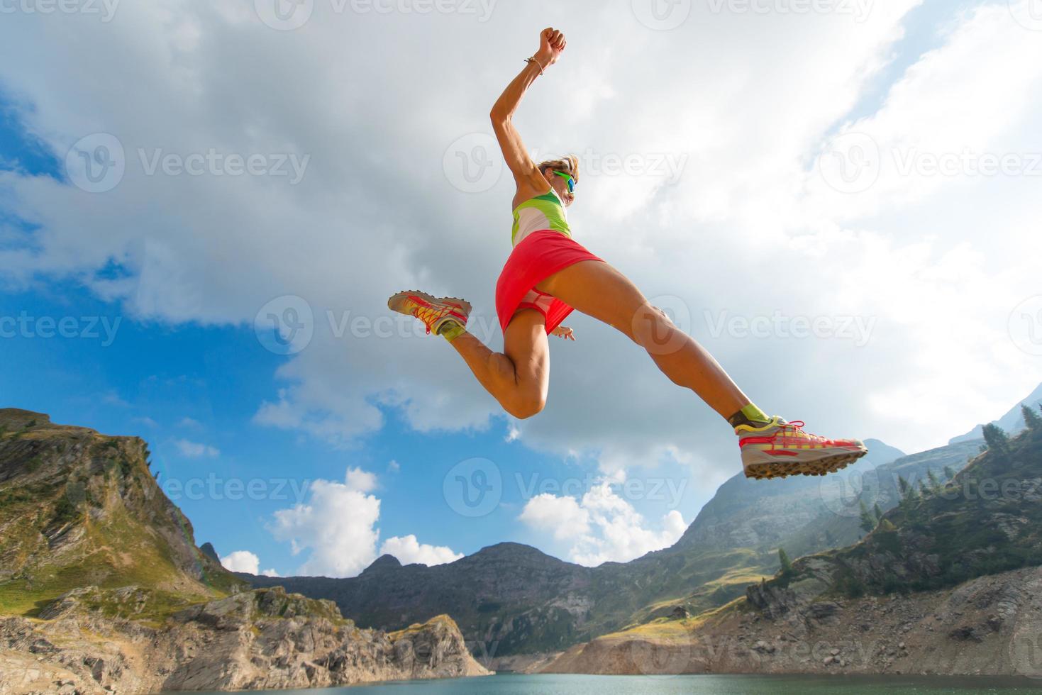 saltando chica mientras corre cerca de un lago de montaña foto
