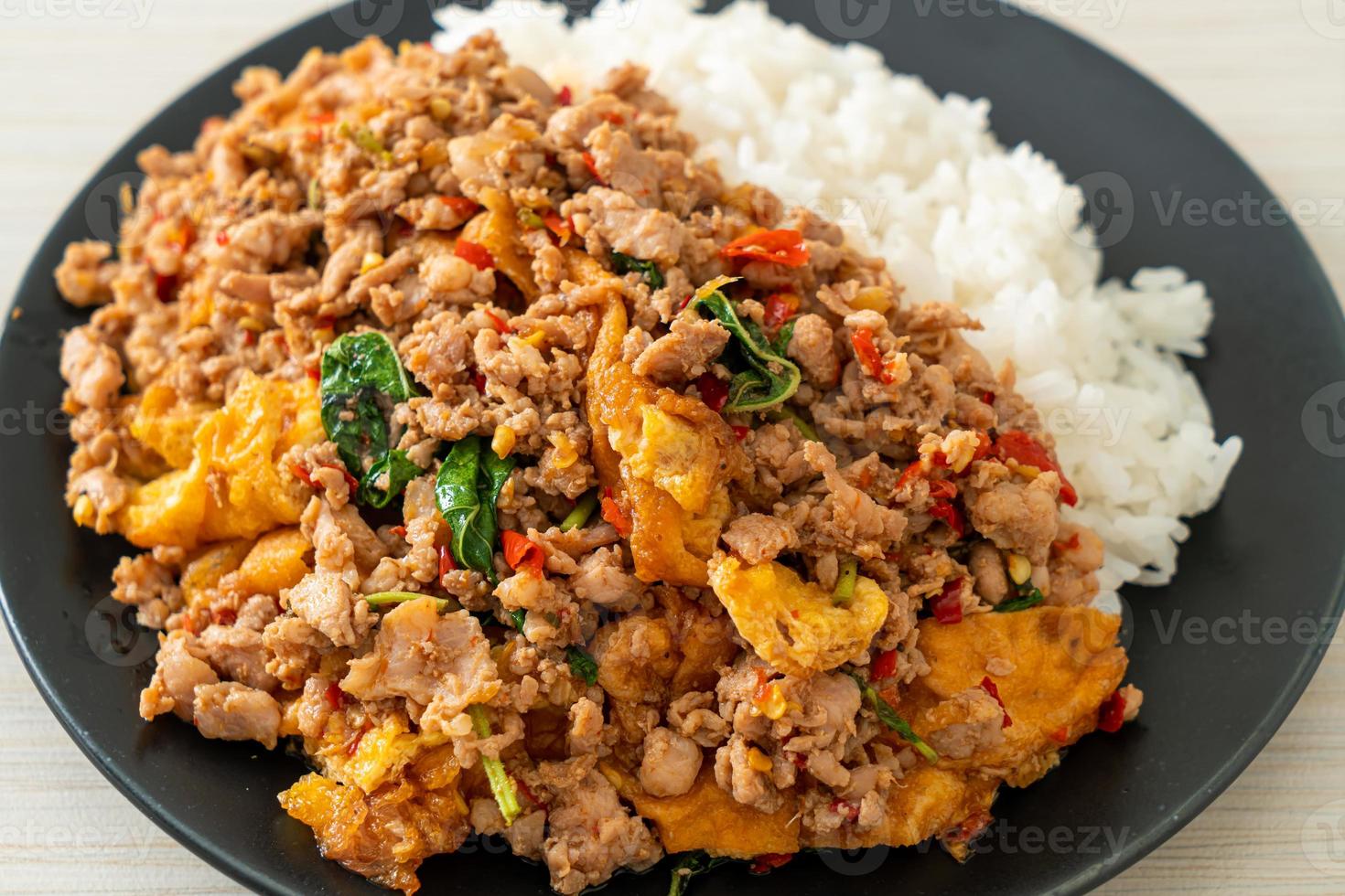 Carne de cerdo picada salteada con albahaca y huevo con arroz - estilo de comida asiática foto