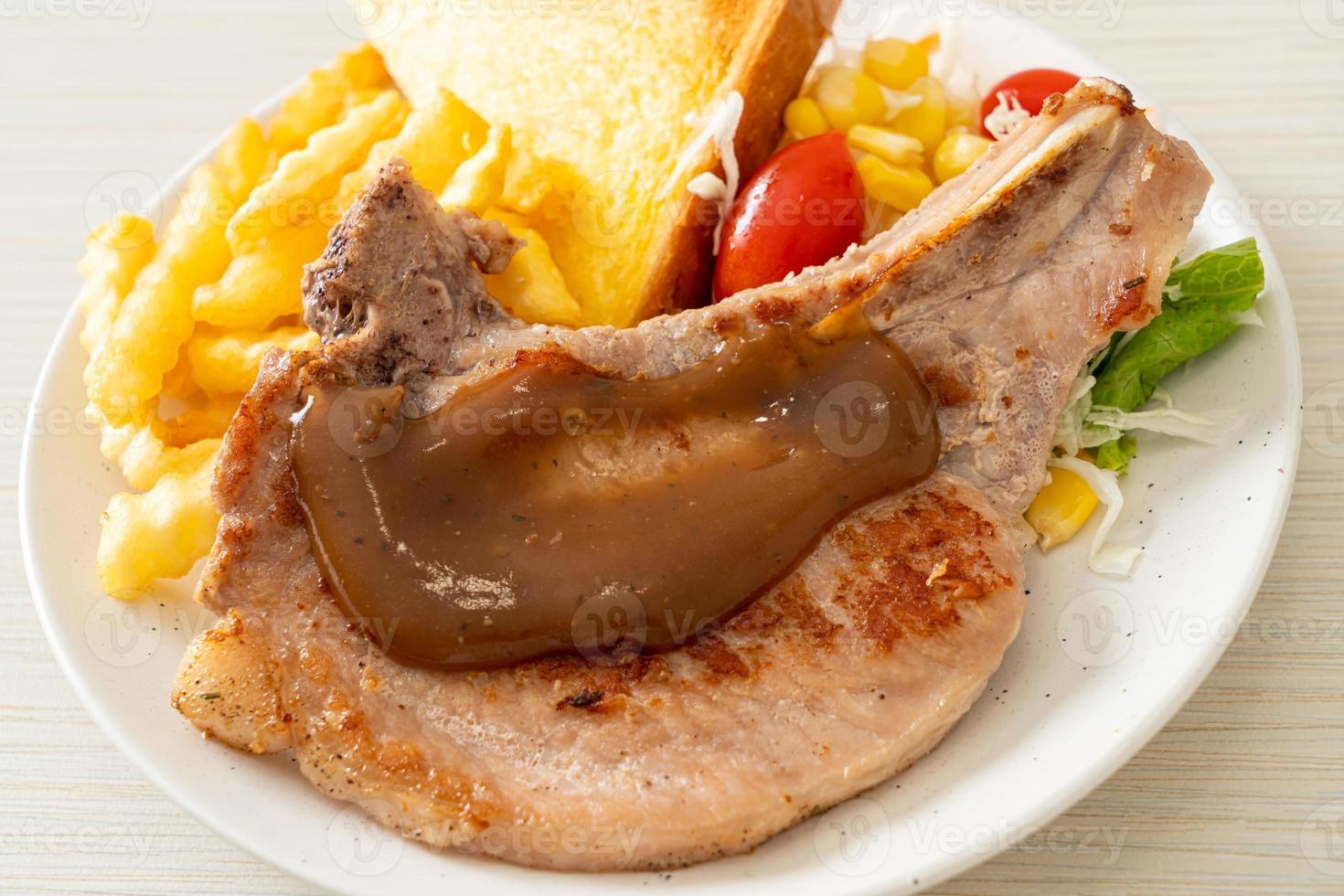 Pork chop steak with chips and mini salad on white plate photo