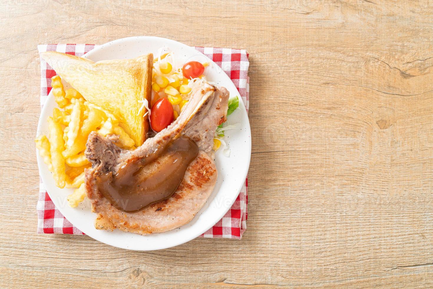 Pork chop steak with chips and mini salad on white plate photo