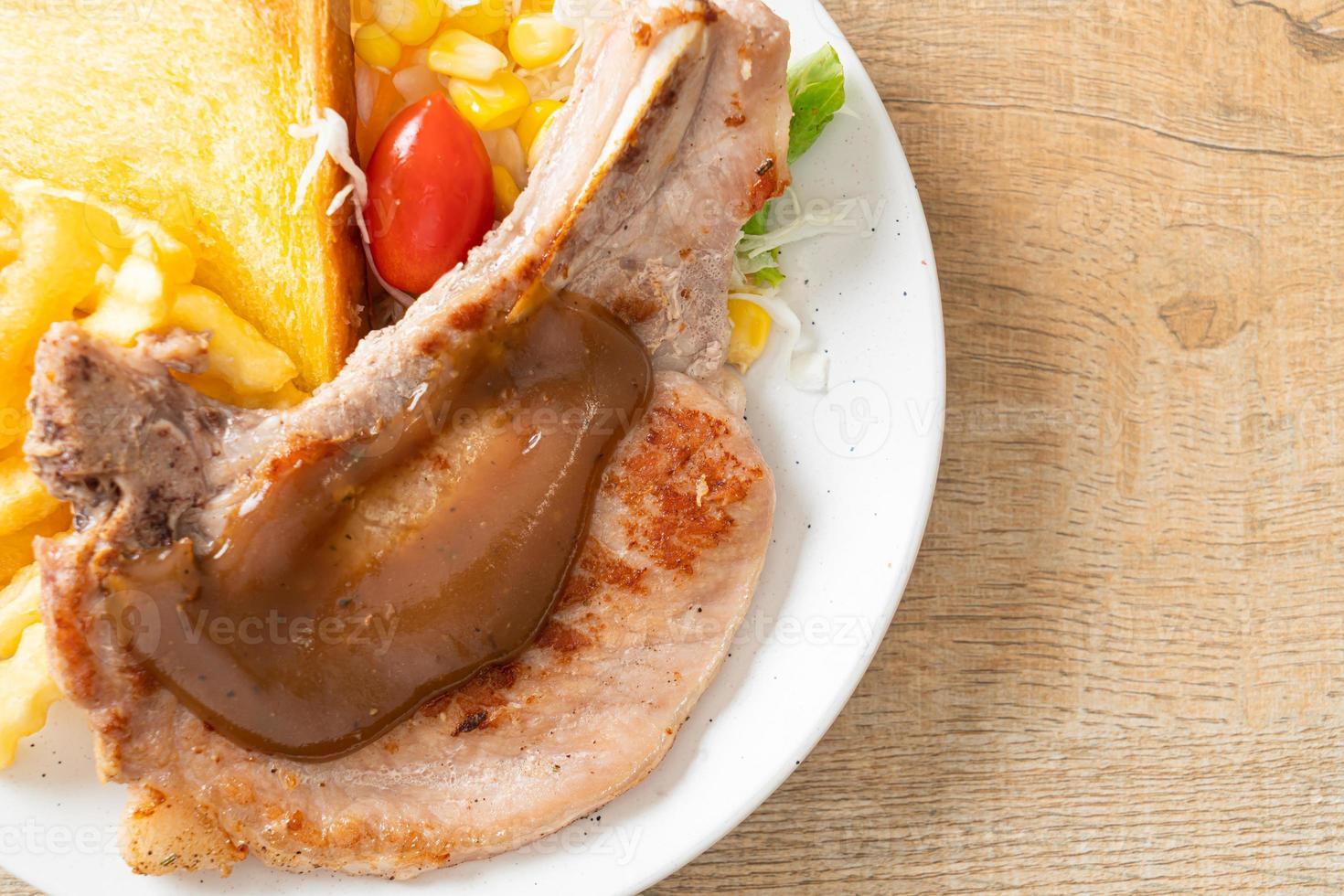 Filete de chuleta de cerdo con patatas fritas y mini ensalada en la placa blanca. foto