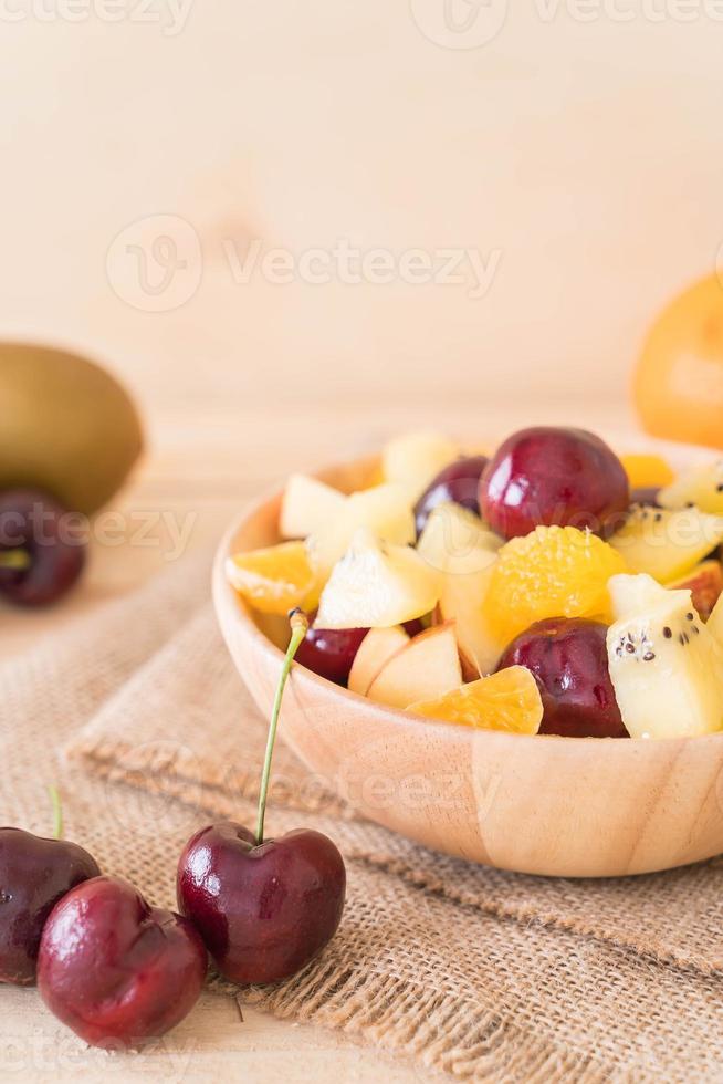 Mixed sliced fruit in wood bowl photo