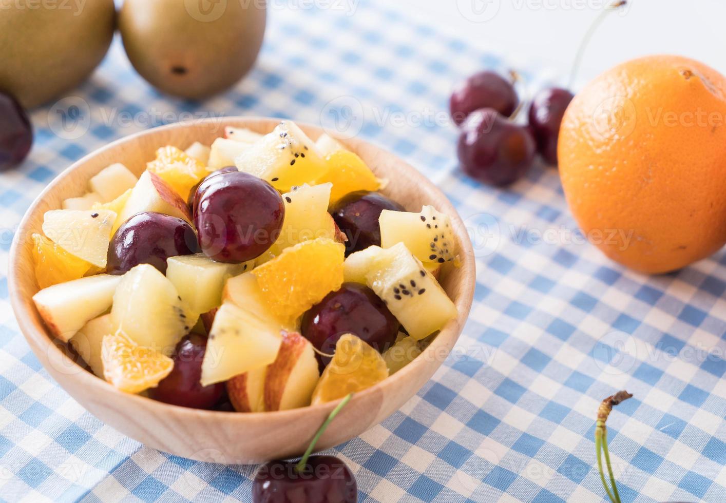 Mixed sliced fruit in wood bowl photo