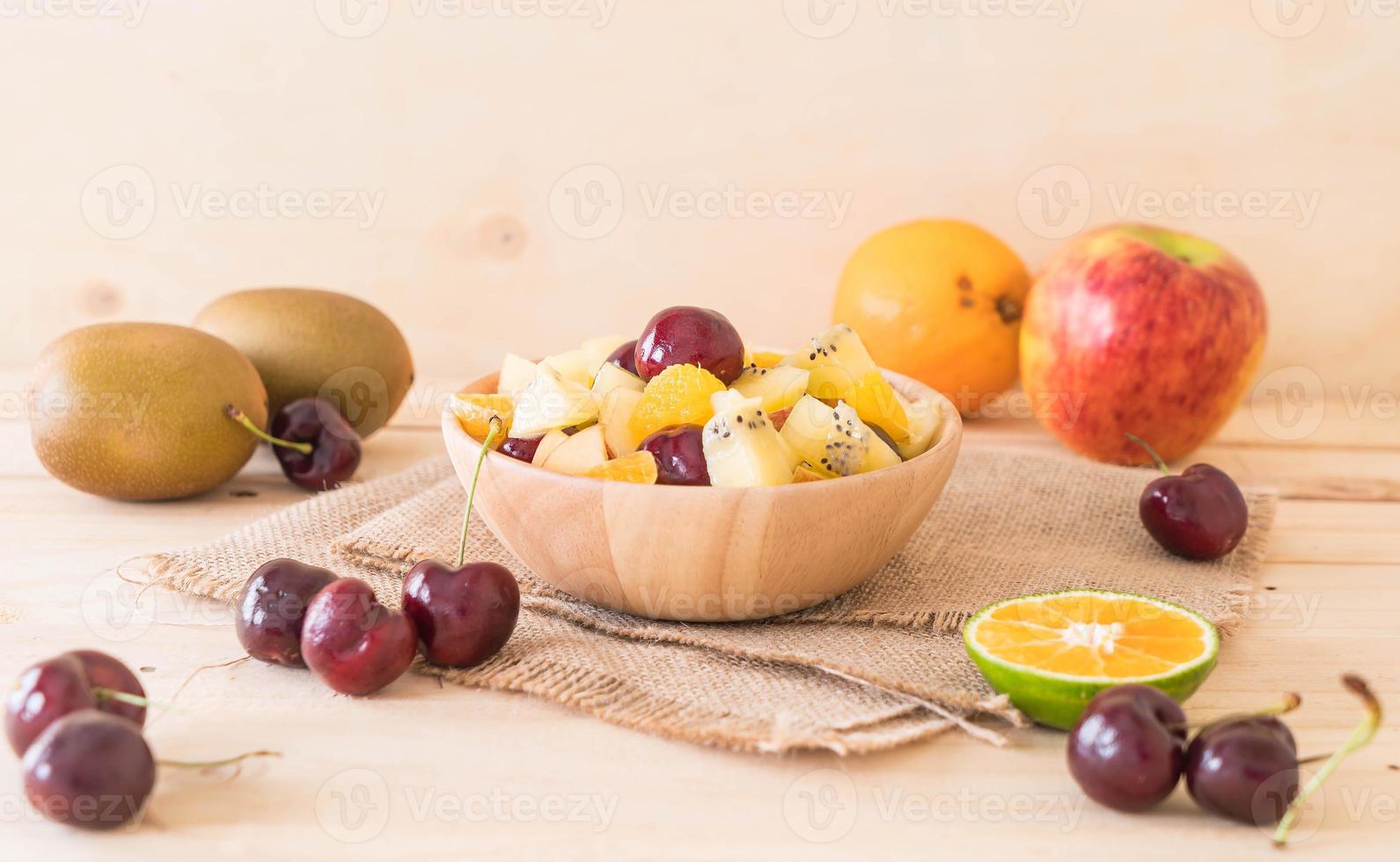 Mixed sliced fruit in wood bowl photo