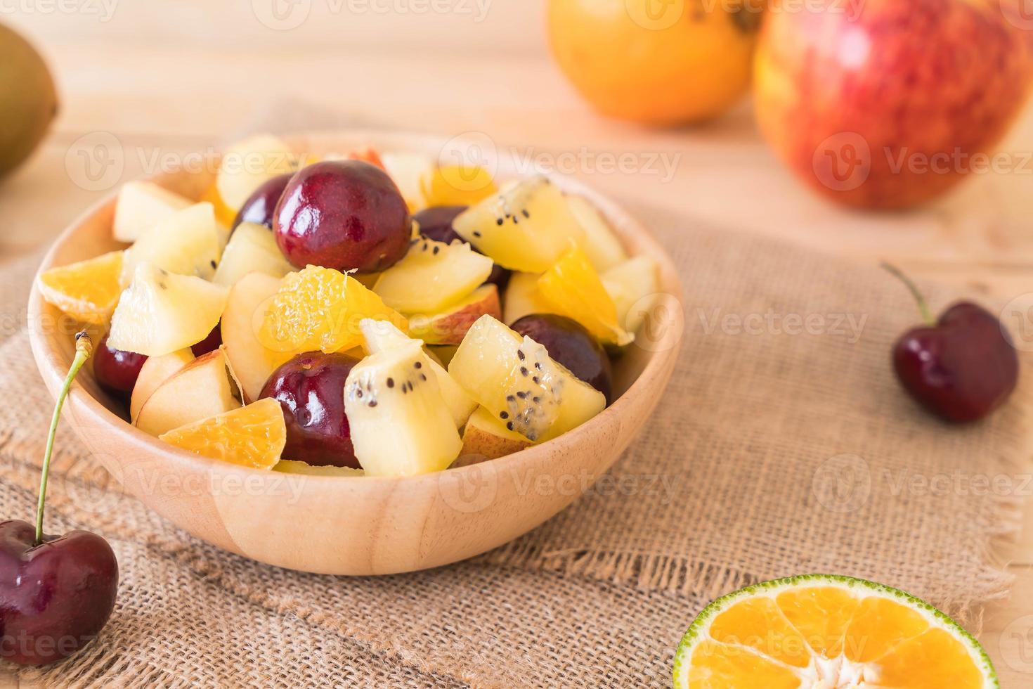 Mixed sliced fruit in wood bowl photo