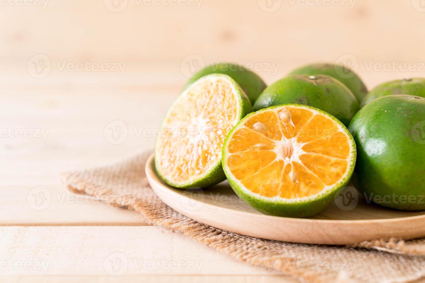Naranja fresca en placa de madera sobre la mesa foto