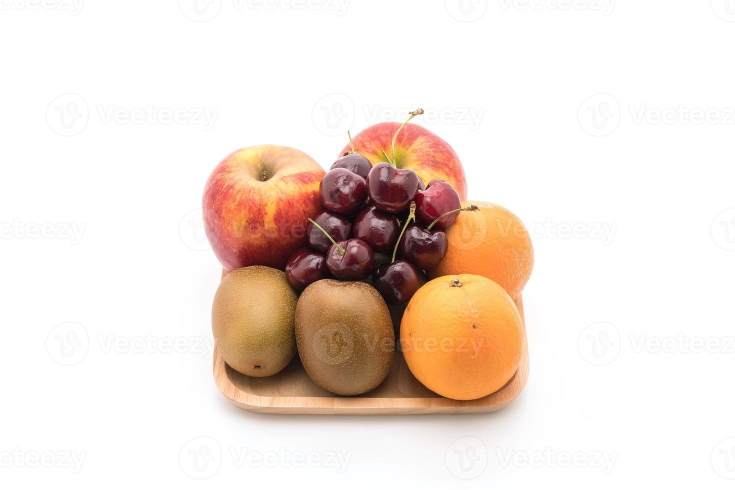 Fruta mixta en placa de madera sobre fondo blanco. foto