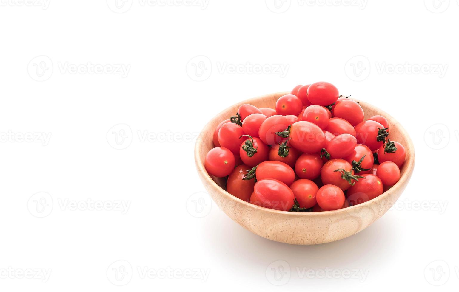 Tomates frescos en un tazón de madera sobre fondo blanco. foto