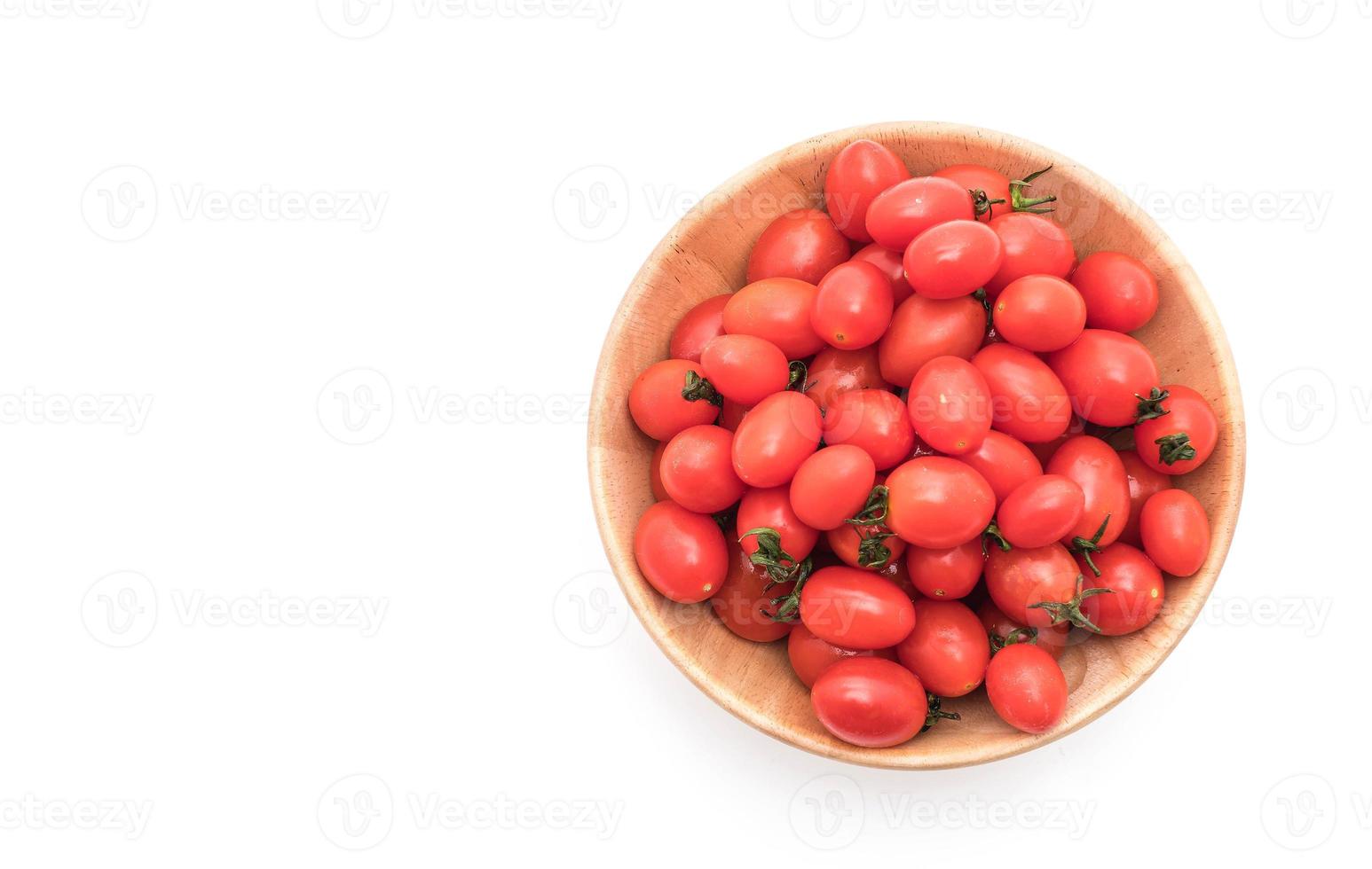 Tomates frescos en un tazón de madera sobre fondo blanco. foto