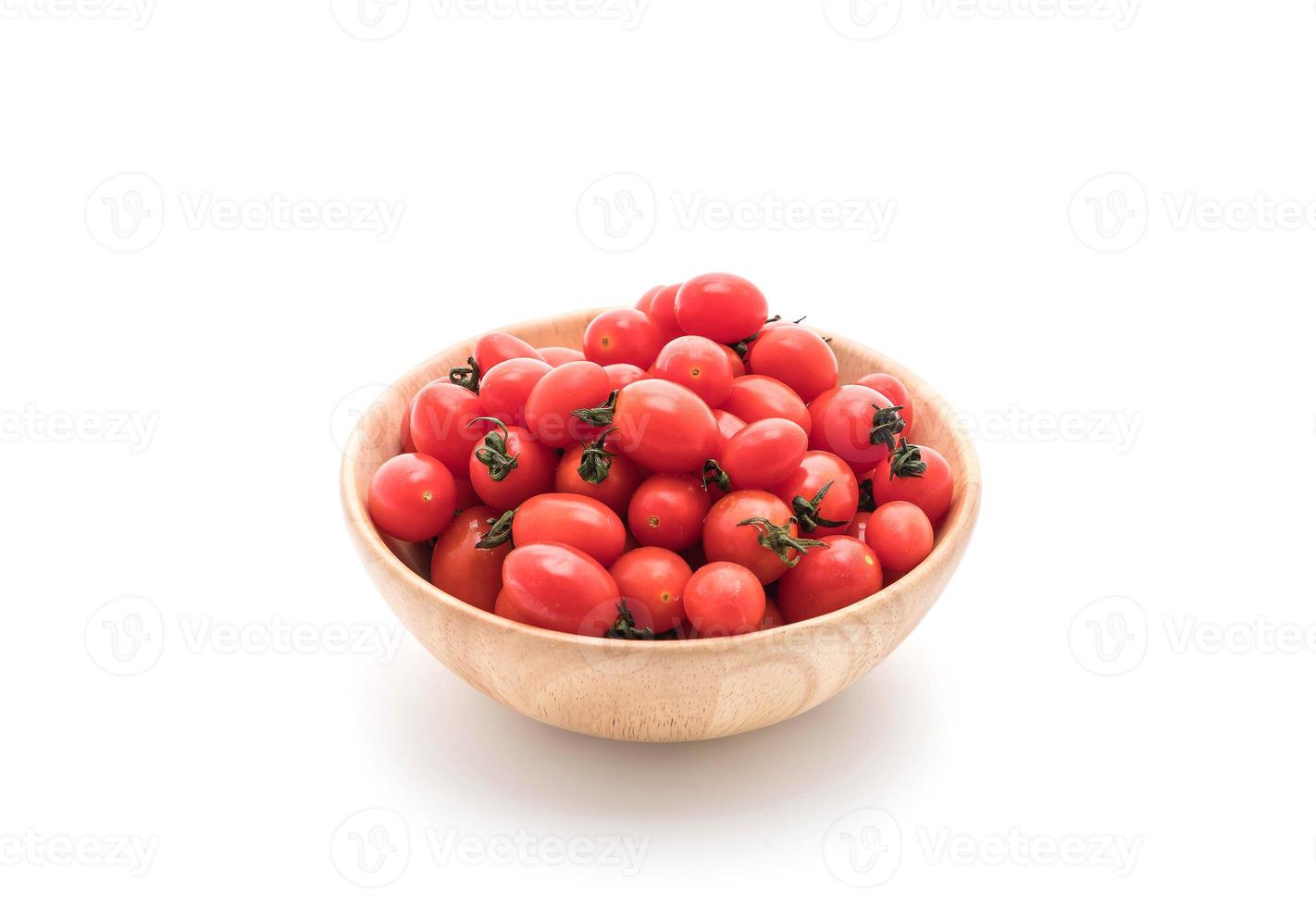 Tomates frescos en un tazón de madera sobre fondo blanco. foto