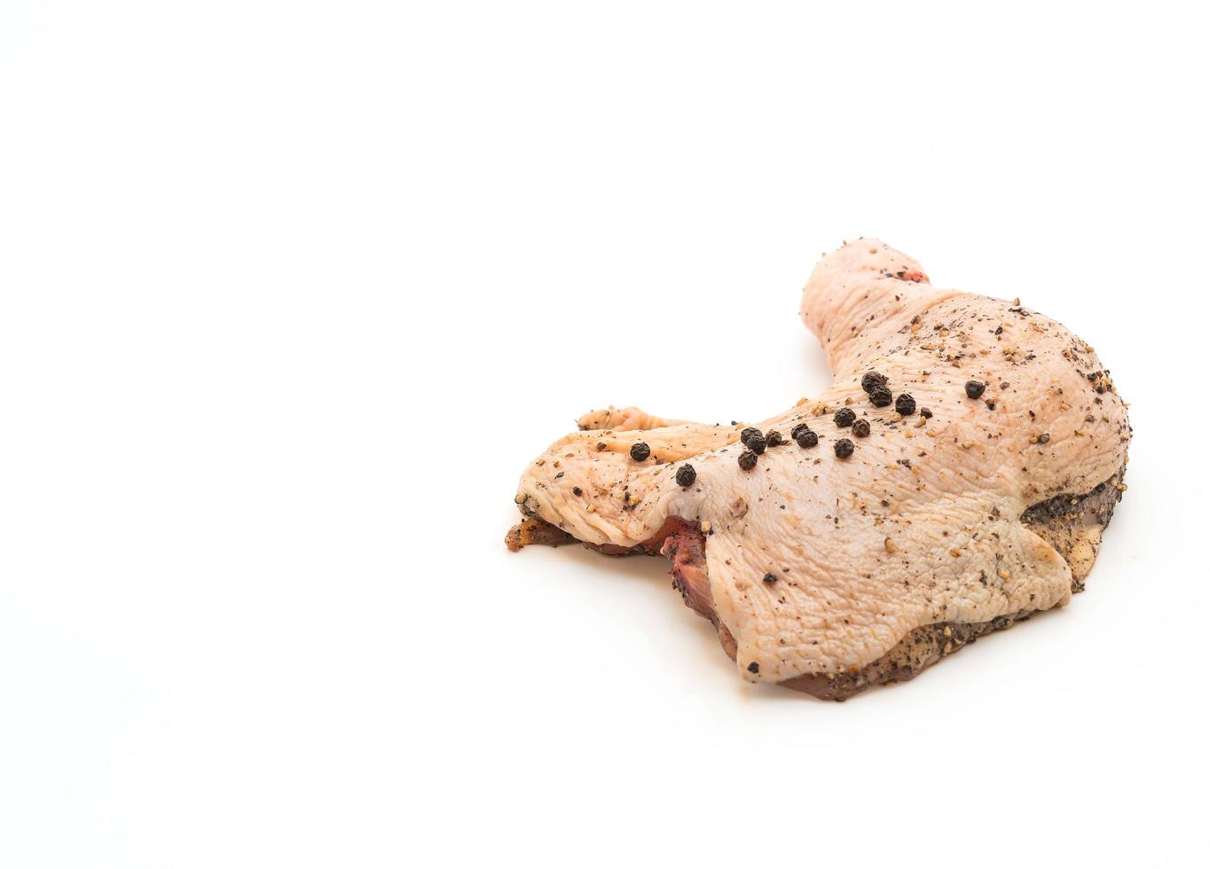 Muslo de pollo marinado con salsa, pimientos negros, ajos y ají seco sobre tabla de madera foto