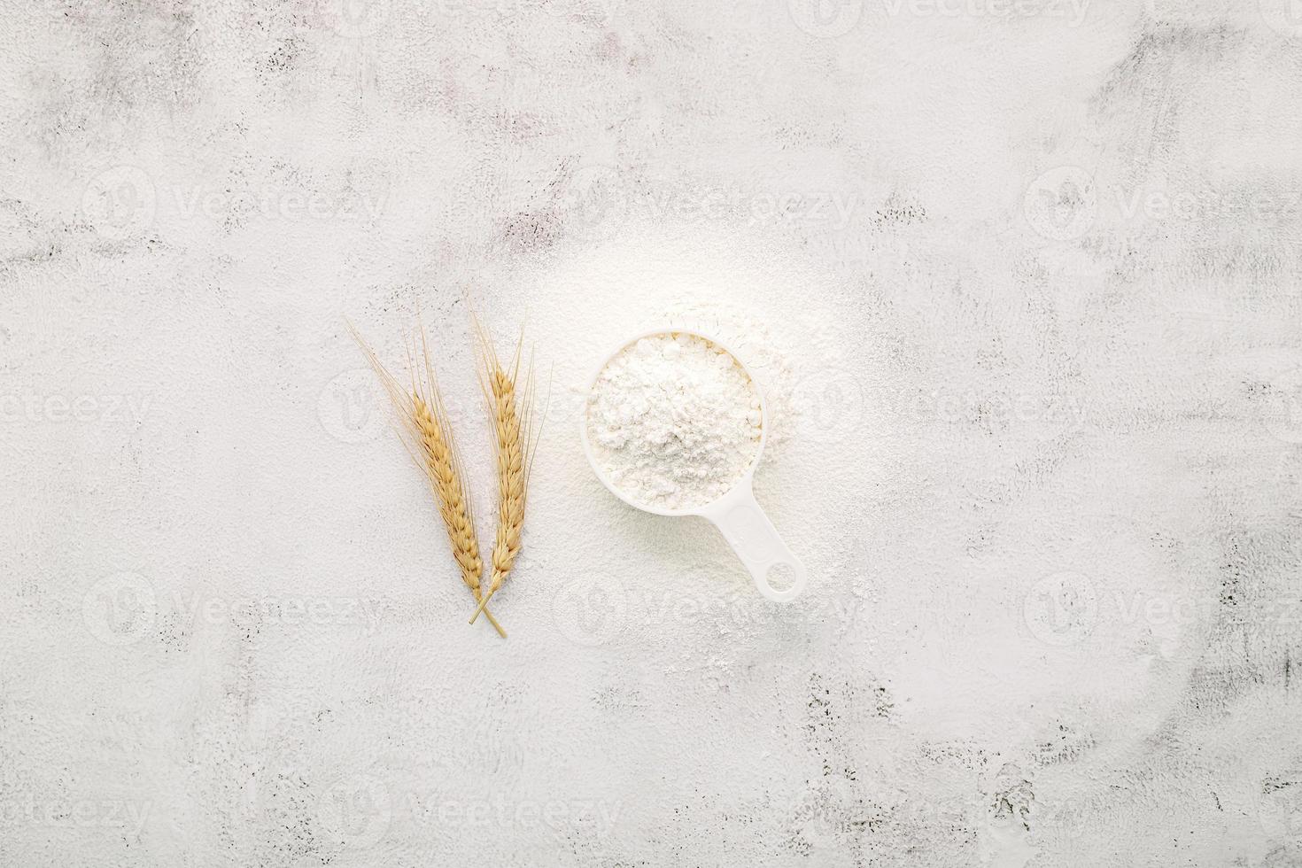 Wheat flour  in wooden bowl set up on white concrete background photo