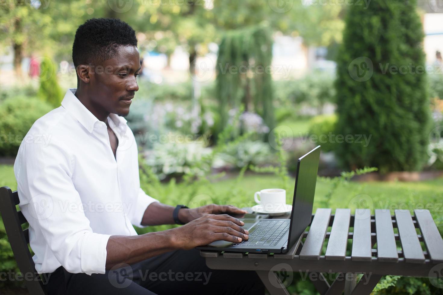 empresario afroamericano, trabaja en una computadora portátil en un café, autónomo foto