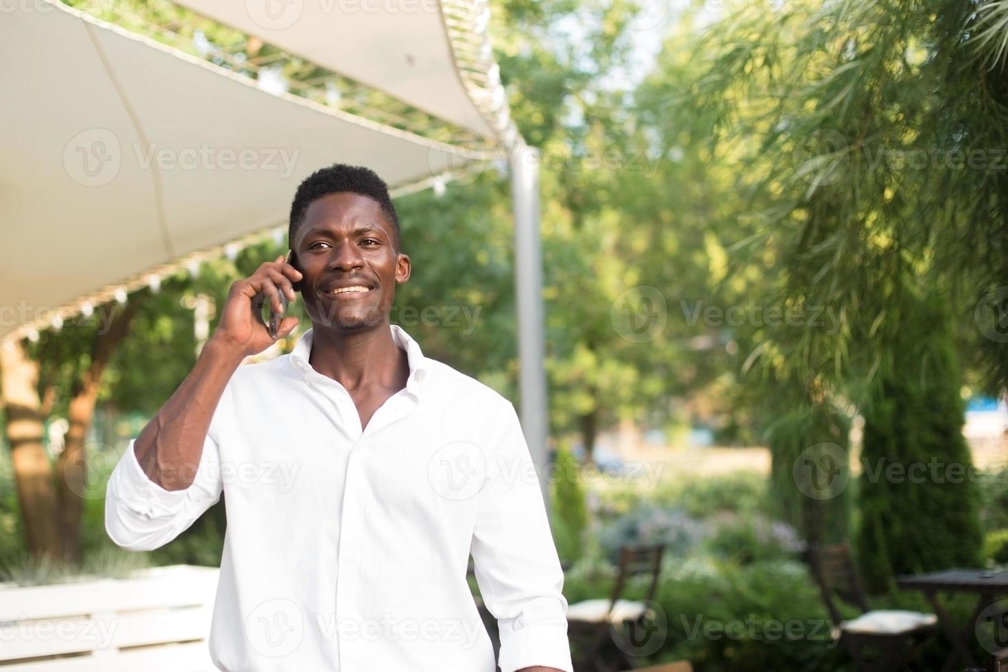 Feliz afroamericano con un teléfono en la calle foto