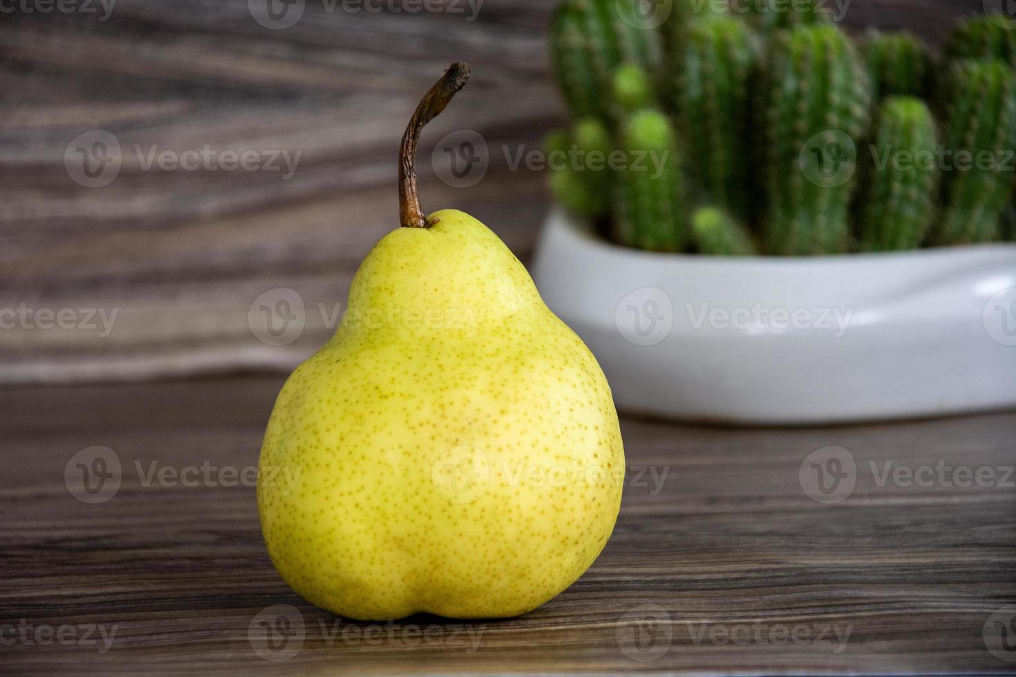 Pear on a wooden background. A yellow pear lies on the table against photo