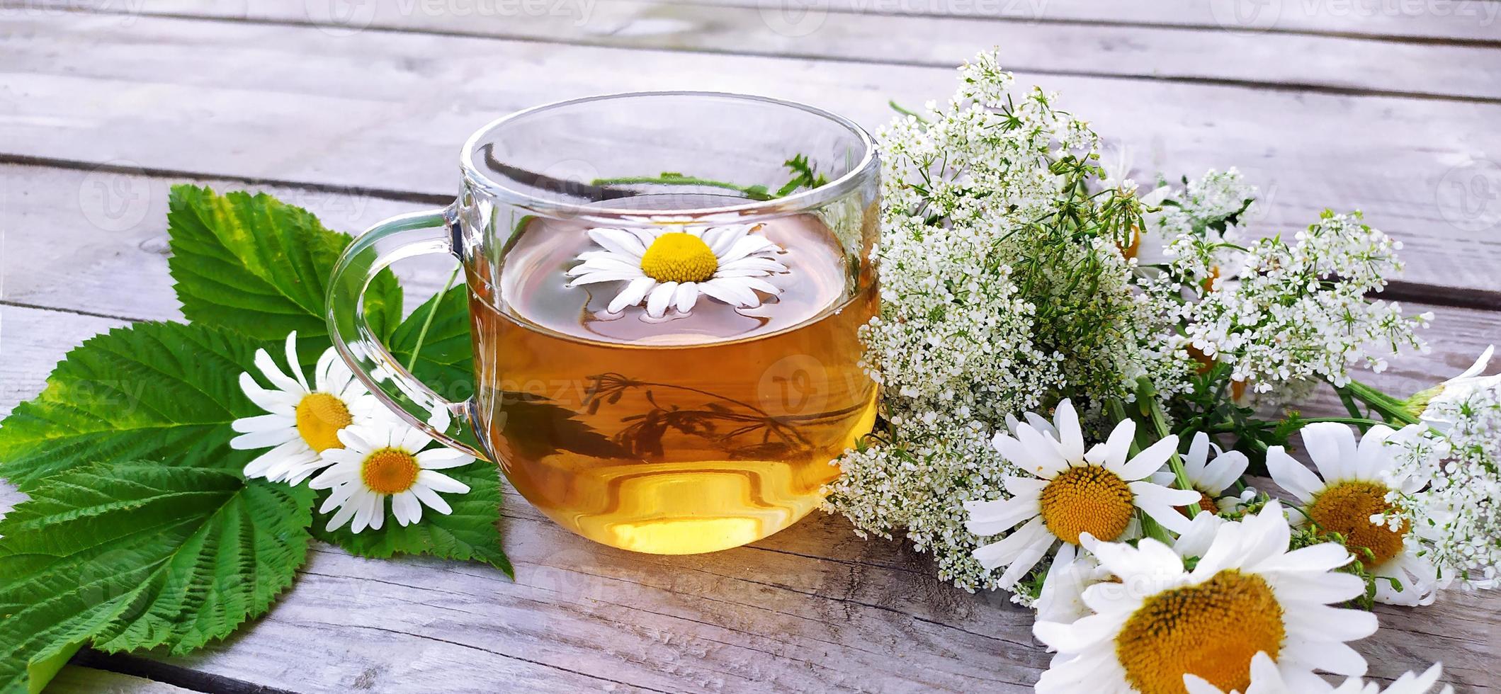 Chamomile aromatic tea in a glass cup on a wooden background. photo