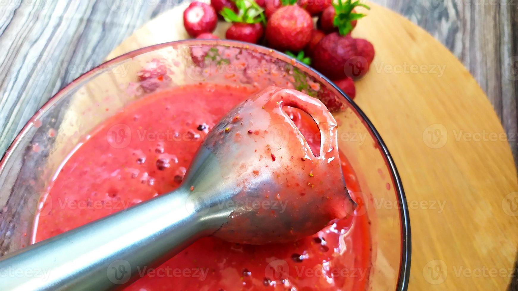 Processing strawberries with an electric blender. photo