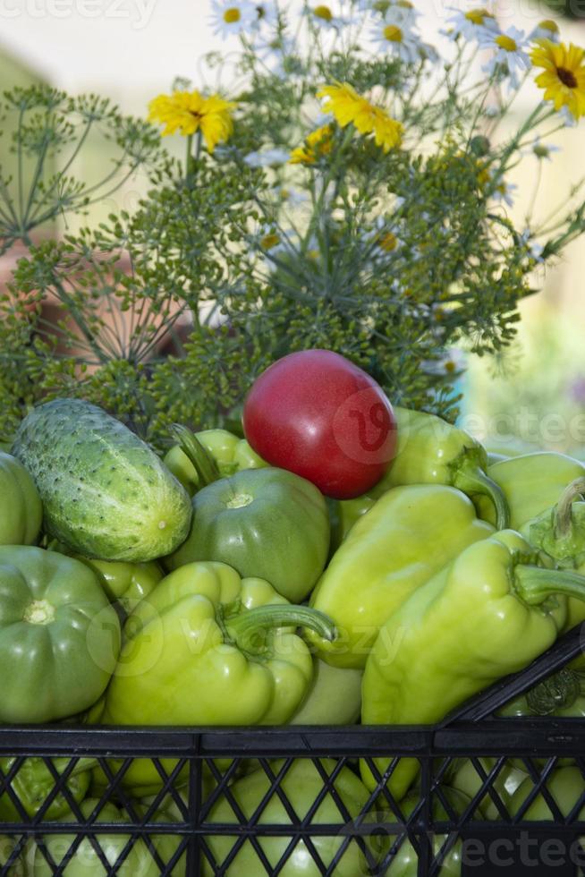 Vegetables in a black box and an armful of wildflowers. photo