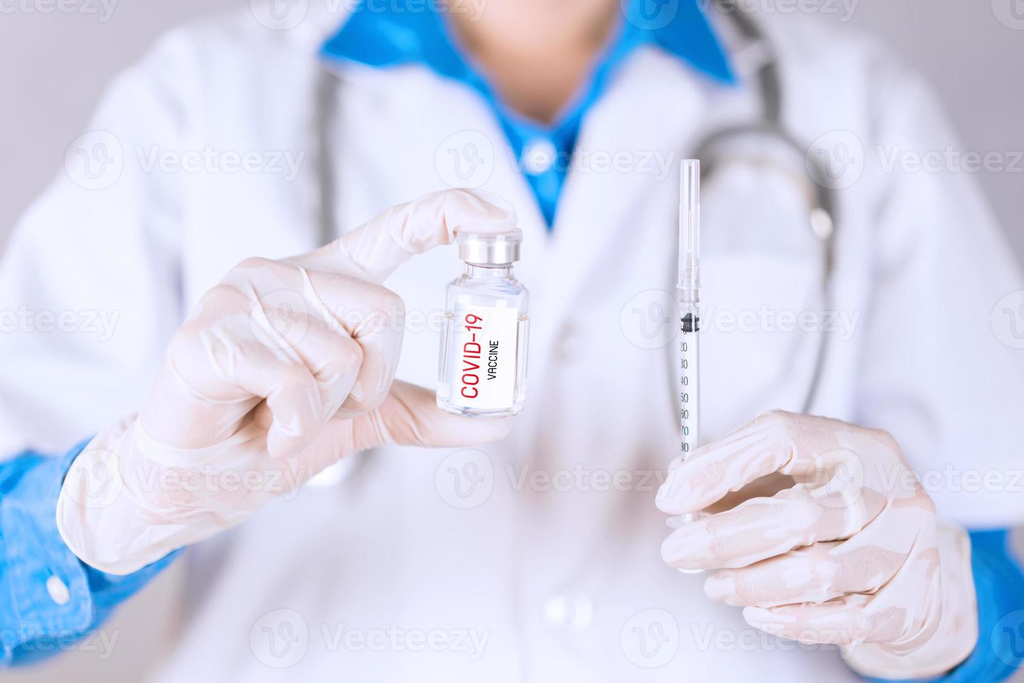 Doctor holding COVID-19 vaccine and syringe for treat and cure photo