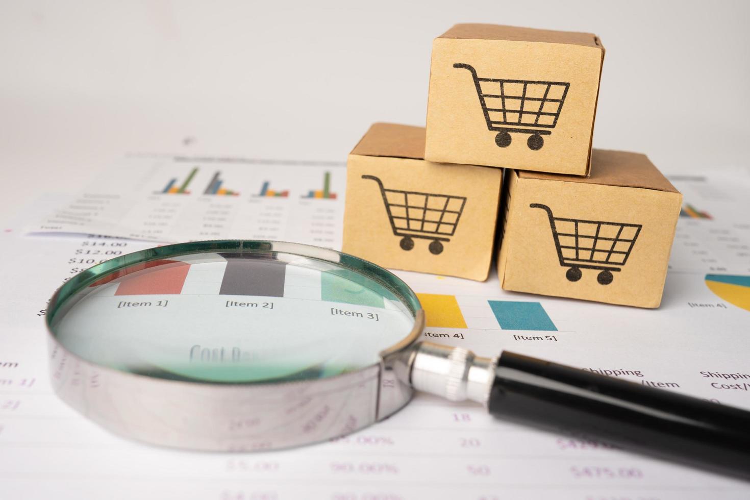 Shopping cart logo on box with magnifying glass on graph photo