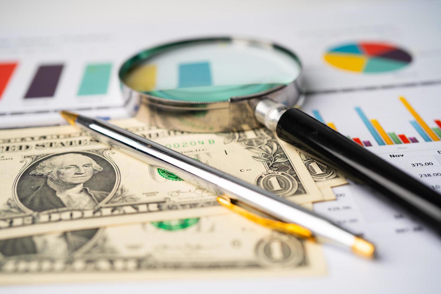 Magnifying glass on charts graphs paper. photo