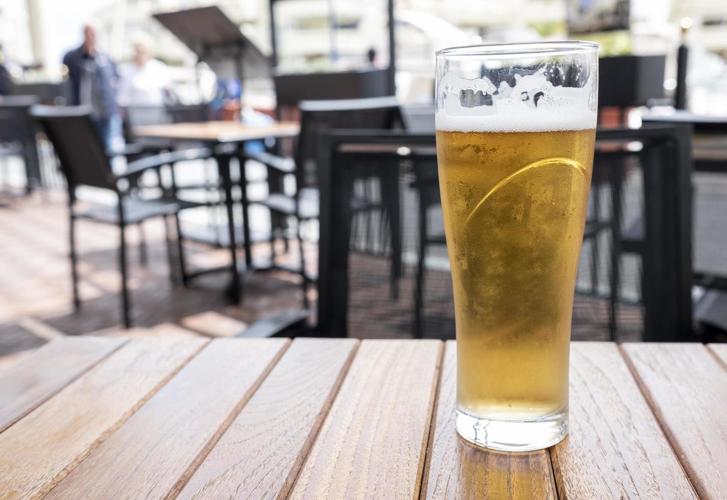 glass of cold beer with foam on a wooden table photo