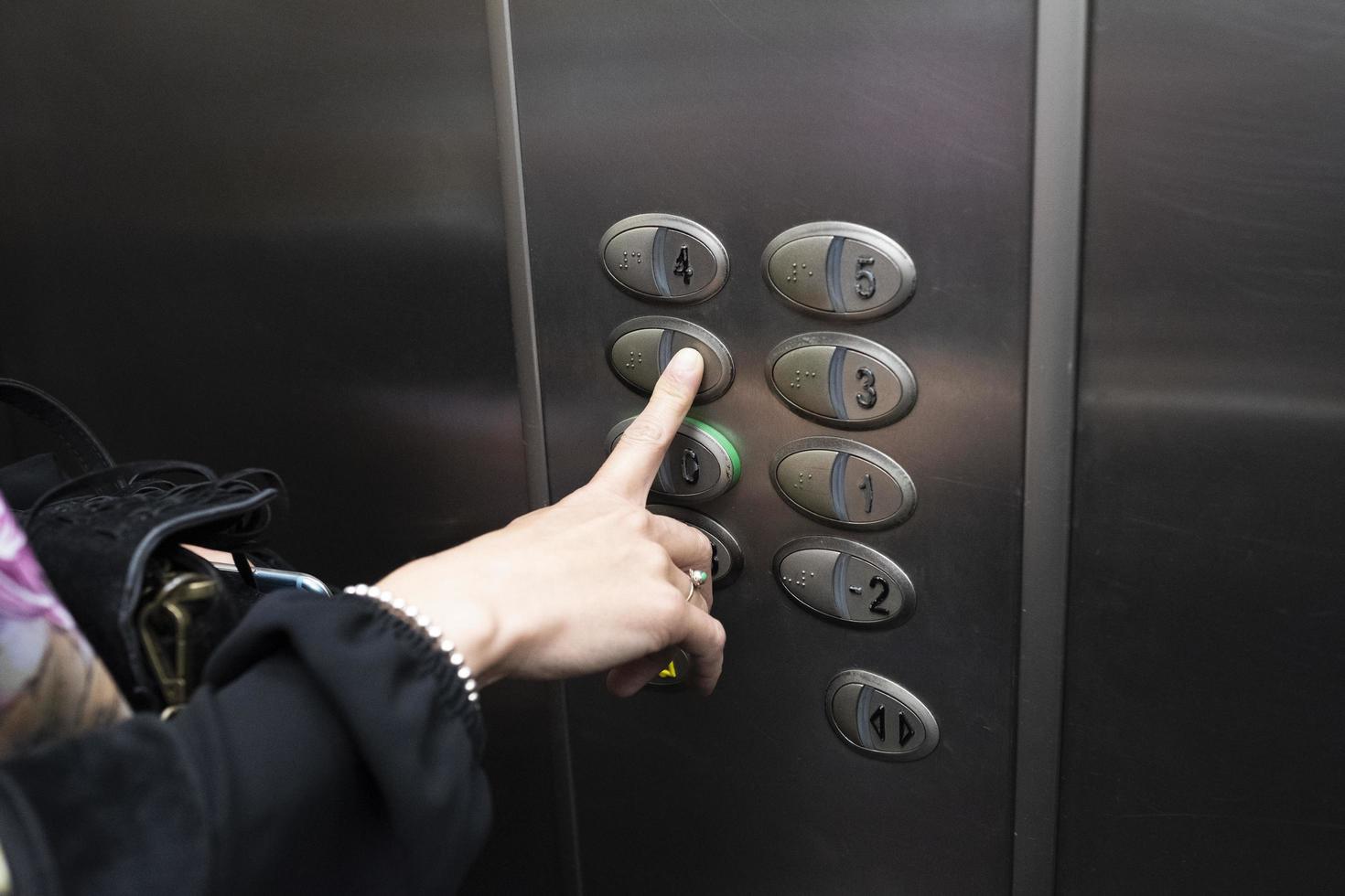 Mujer dentro de un ascensor presionando un botón de la caja. foto