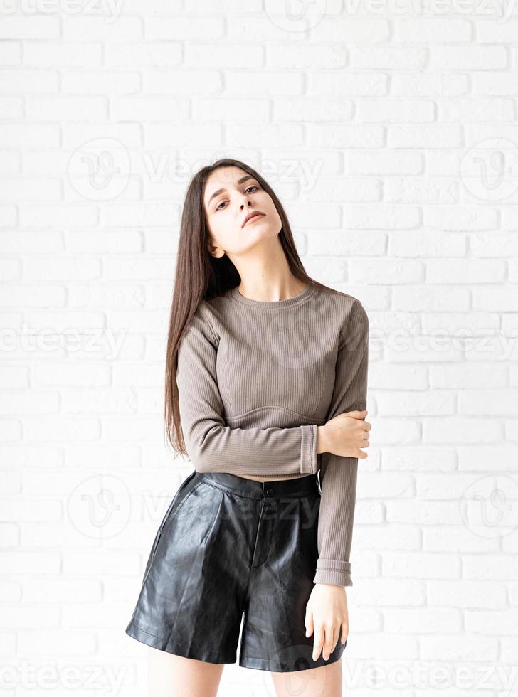 woman with long hair posing on white brick wall background photo