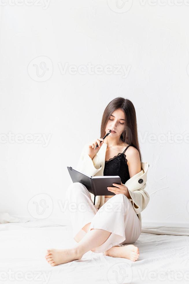 woman in comfy home clothes writing notes sitting on the floor photo