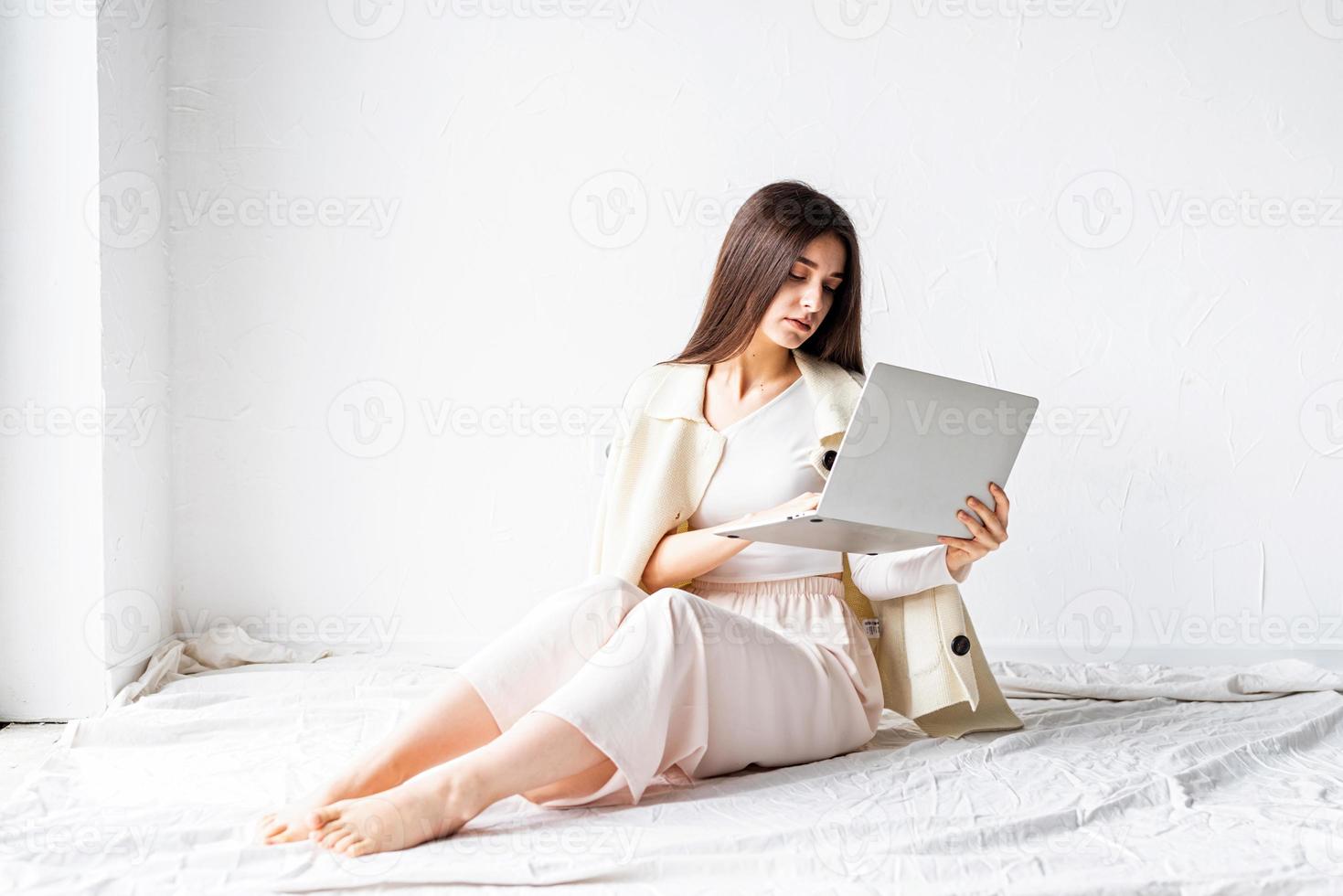 Mujer sentada en el suelo y haciendo un proyecto independiente en la computadora portátil foto